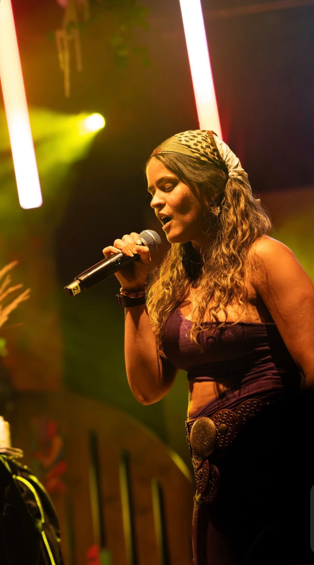 Chika Toro singing into a microphone under stage lights